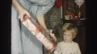 Kansas City Missouri (1959): A Young Child In Pajamas Happily Unwrapping A