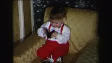 LYNBROOK NEW YORK-1975: Well Dressed Young Boy Plays With A Small Book Or Case