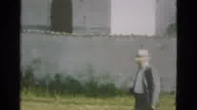 Denmark (1975): Man Wearing A Hat And Suit Carrying A Camera Is Led Into A