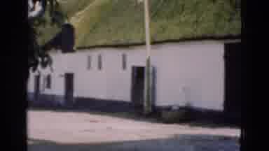 Denmark (1975): The Side Of An Old White Building With Moss Colored Roof