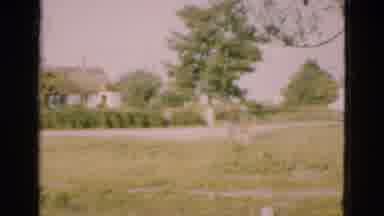 Denmark (1975): People Walking In Green Field While Green Car Drives By On Road On
