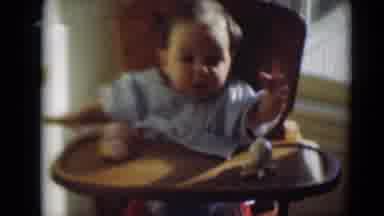 MIDDLETOWN PENNSYLVANIA-1975: Baby In High Chair Waves And Curls Fingers As Baby