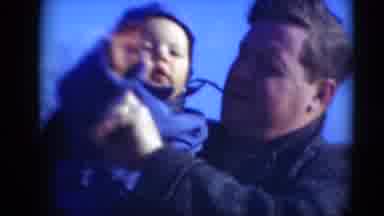 Middletown Pennsylvania (1975): Father Waving Baby's Hand To Camera While They're