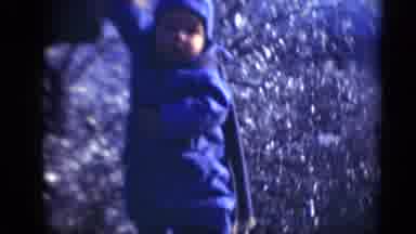 Middletown Pennsylvania (1975): Person Helps Baby Wearing Blue Snowsuit To Stand