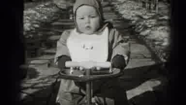 Middletown Pennsylvania (1975): Young Child Wearing A Bib And Hoodie Is Riding A
