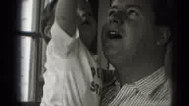 Middletown Pennsylvania (1975): Man Holds And Kisses Baby Wearing White Penn State