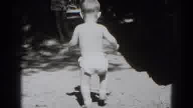 Middletown Pennsylvania (1975): Baby Wearing White Diaper Walks To Wooden Display