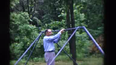 Somerset Kentucky USA (1975): Older Man Swinging From Swing Set Bar In Formal