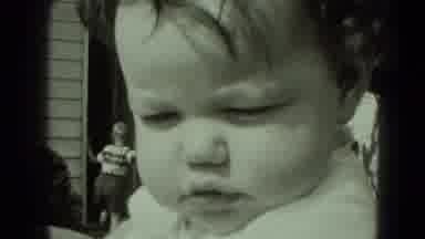 Middletown Pennsylvania (1975): Baby Wearing White Shirt Looks At Camera On A
