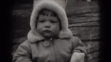 Middletown Pennsylvania (1975): Baby Wearing White Coat Looks At Camera On A Sunny
