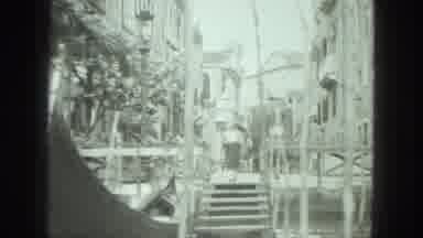 Venice Italy-1975: Woman Standing By Canal As Gondola Travels Past