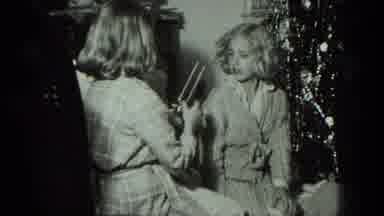 MILWAUKEE WISCONSIN USA-1975: Young Girls Unwrap Christmas Presents Next To Tree