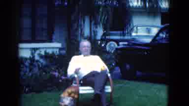 Florida USA (1975): Grandfather Sitting Down On The Front Lawn Chair With A Bag Of