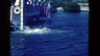 Florida USA (1975): Man Standing On Dock Holds Up A Treat For A Jumping Dolphin As