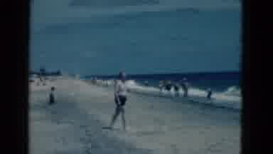 Florida USA (1975): Man Walks Across The Beach Towards The Ocean As The Waves Lap