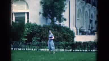 Florida USA (1975): A Woman In A Dress Walking On The Grass In Front Of Small