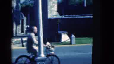 Florida USA (1975): Man On Bike Rides By Stone Tower And American Flag Flying High