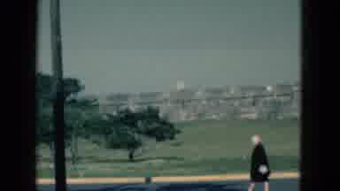 Florida USA (1975): Old Woman Walks Down A Busy Highway With Cars Passing