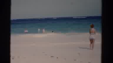 Florida USA (1975): A Woman Looks On As People Play In The Waves At The Beach