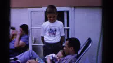 Florida USA-1975: Father Holds Sleeping Baby As Son Stands Nearby