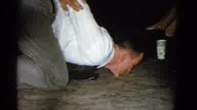 Boston Mass USA (1975): Man Wearing White Shirt Picks Up Straw With Teeth From