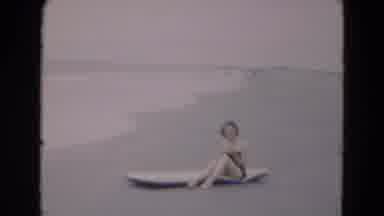 Florida USA-1975: Woman Sits On A Surfboard Next To The Ocean As Waves Hit The