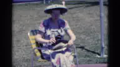 Florida USA (1975): Woman In A Floral Dress Wears Large Visor Sits To Read The