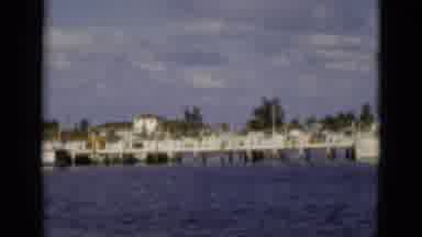 Florida USA (1975): A Large Boat Dock And A Boat Passing By With A House On A Hill