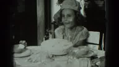 West Germany (1951): Young Girl Sitting At A Table Happily Blowing Out The Candles