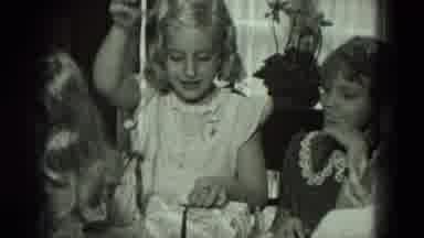 WEST GERMANY-1951: Girl in White Dress Unwraps Gift at Birthday Party