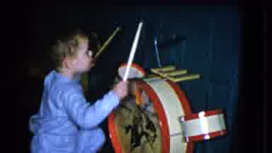 Cleveland Ohio (1951): Excited Child Hitting A Toy Drum Set While Wearing A Blue
