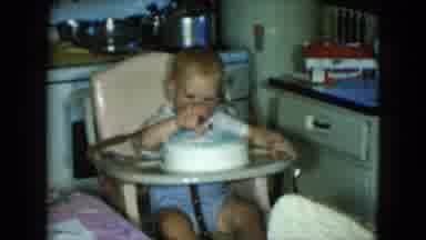 Cleveland Ohio (1951): Baby Wearing Blue Shorts Sits In Tan Highchair Looking