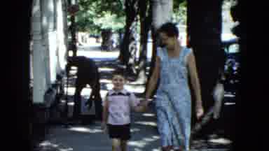 Cleveland Ohio (1951): Happy Little Boy Walking Down A Sidewalk Holding A Woman's
