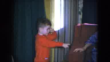 Cleveland Ohio (1951): Small Boy Wearing Red Shirt Rubs Eye And Points At Sitting