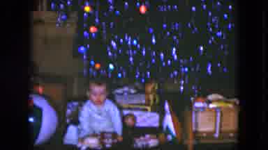 Cleveland Ohio (1951): Baby Wearing Blue Pajamas Sits In Front Of Lit Trimmed