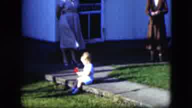 Cleveland Ohio (1951): Young Child Sitting On A Sidewalk Holding A Red Toy While