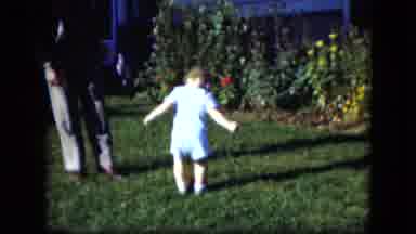 CLEVELAND OHIO-1951: Baby Wearing Blue Dress Tries To Kick Red Ball On A Sunny Day