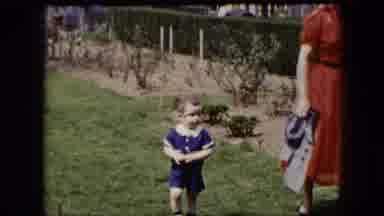 Cleveland Ohio (1951): Boy Wearing Blue Jumpsuit Walks Beside Woman Wearing Red