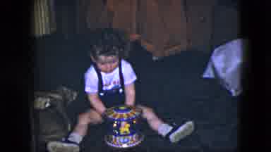 Cleveland Ohio (1951): A Little Boy Wearing Overalls Sits On The Floor And Plays