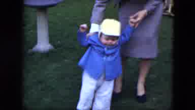 Cleveland Ohio (1951): Woman Wearing Grey Suit Helps Baby Wearing Blue Coat Walk