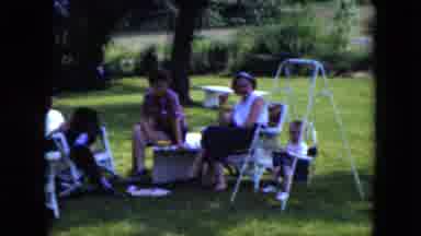 Cleveland Ohio (1951): People Sitting In White Chairs With Baby Swing Under Tree