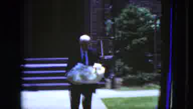 Cleveland Ohio (1951): Older Man Wearing Suit Carries Baby In Basket Then Woman