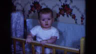 Cleveland Ohio (1951): Child Standing In Wooden Crib With Blankets Wearing White