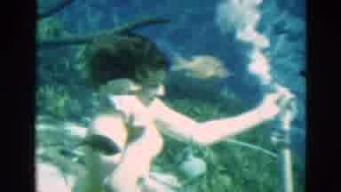 Florida USA (1952): Woman Wearing Yellow Swimwear Inserts Air Tube Into Mouth