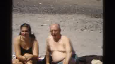 California USA (1953): Two Men And A Women Sitting Together In The Sun On A Beach