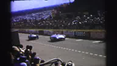 Le Mans France (1954): Race Cars Pace By On A Race Track As The Packed Stands Of