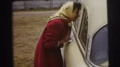 Le Mans France (1954): Woman Peers Into Window Of An Old Yellow Car With Scarf On