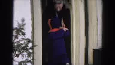 Hicksville New York-1954: Smiling Elderly Woman In Black Dress Helps A Toddler Enter Home