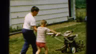 California USA (1954): A Little Child Cutting Grass In His Garden Using Help Of