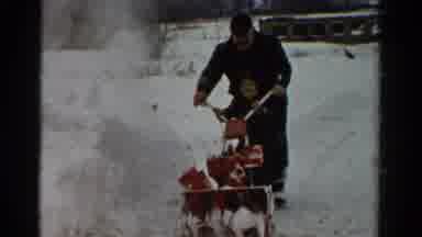 Toledo Ohio USA (1954): Man Wearing Black Snowsuit Uses Snowblower On A Clear
